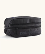 Patagonia black hole 6 litre cube bag in all black with a double zip fastener showing the brand print on front panel