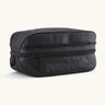 Patagonia black hole 6 litre cube bag in all black with a double zip fastener showing the brand print on front panel