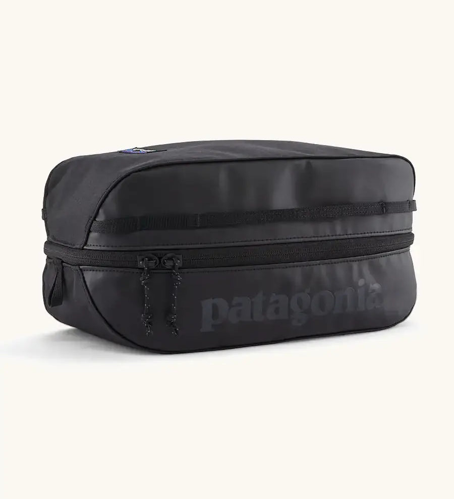 Patagonia black hole 6 litre cube bag in all black with a double zip fastener showing the brand print on front panel