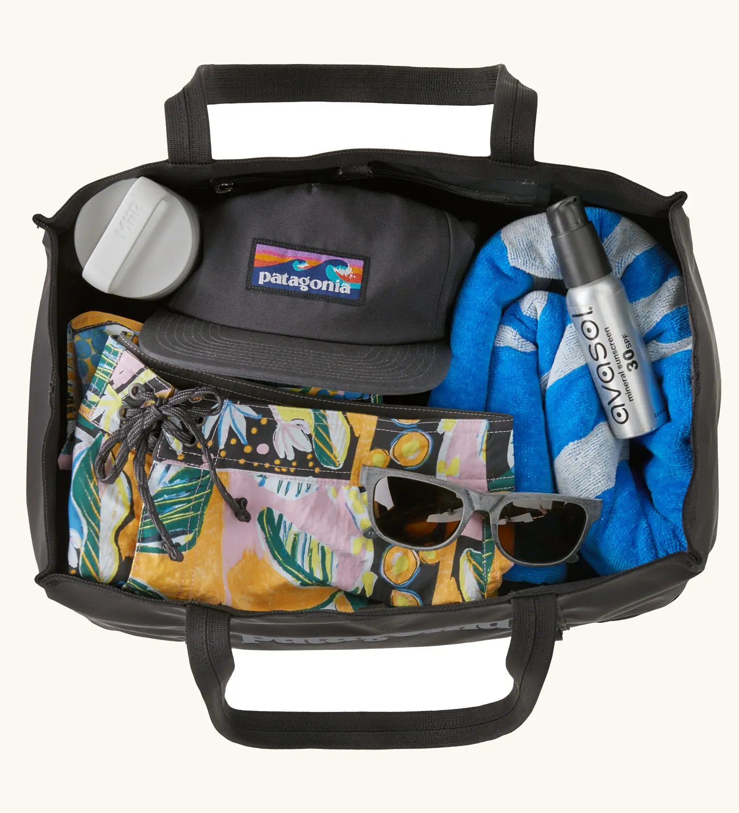 An open Patagonia weather resistant packable black hole 25 litre tote bag in black showing clothing items inside