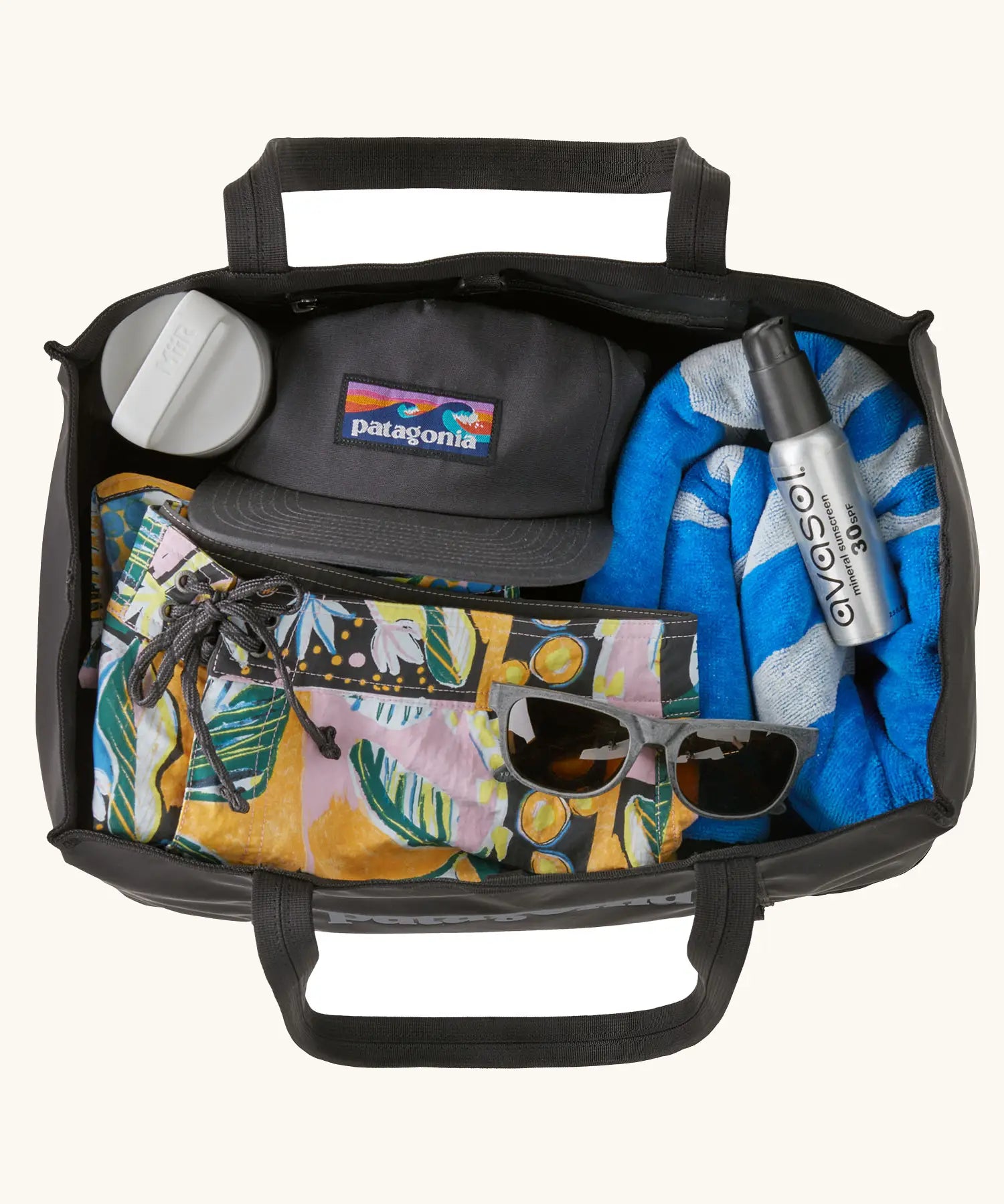 An open Patagonia weather resistant packable black hole 25 litre tote bag in black showing clothing items inside