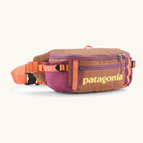Patagonia black hole waist 5L pack in pale orange with 2 compartments and purple mesh side pockets and clip buckle fastener 