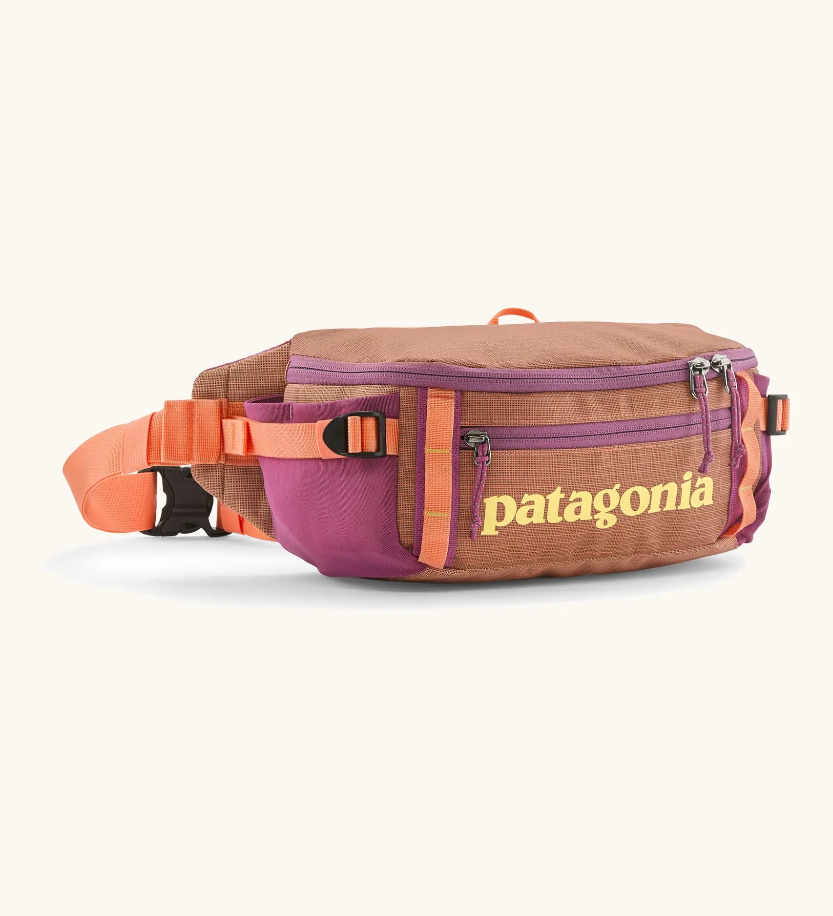 Patagonia black hole waist 5L pack in pale orange with 2 compartments and purple mesh side pockets and clip buckle fastener 