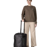 Woman holding the retractable handle on the Patagonia 40 litres black hole wheeled duffel bag in all black 