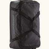Patagonia black hole 70 litre wheeled duffel bag in black. Features extra loops on the side for attaching small items, carry straps and retractable handle
