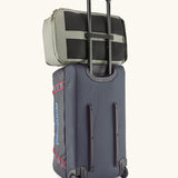 Back of the Patagonia black hole 70 litre wheeled duffel bag in dark blue showing a backpack threaded through the retractable handle 