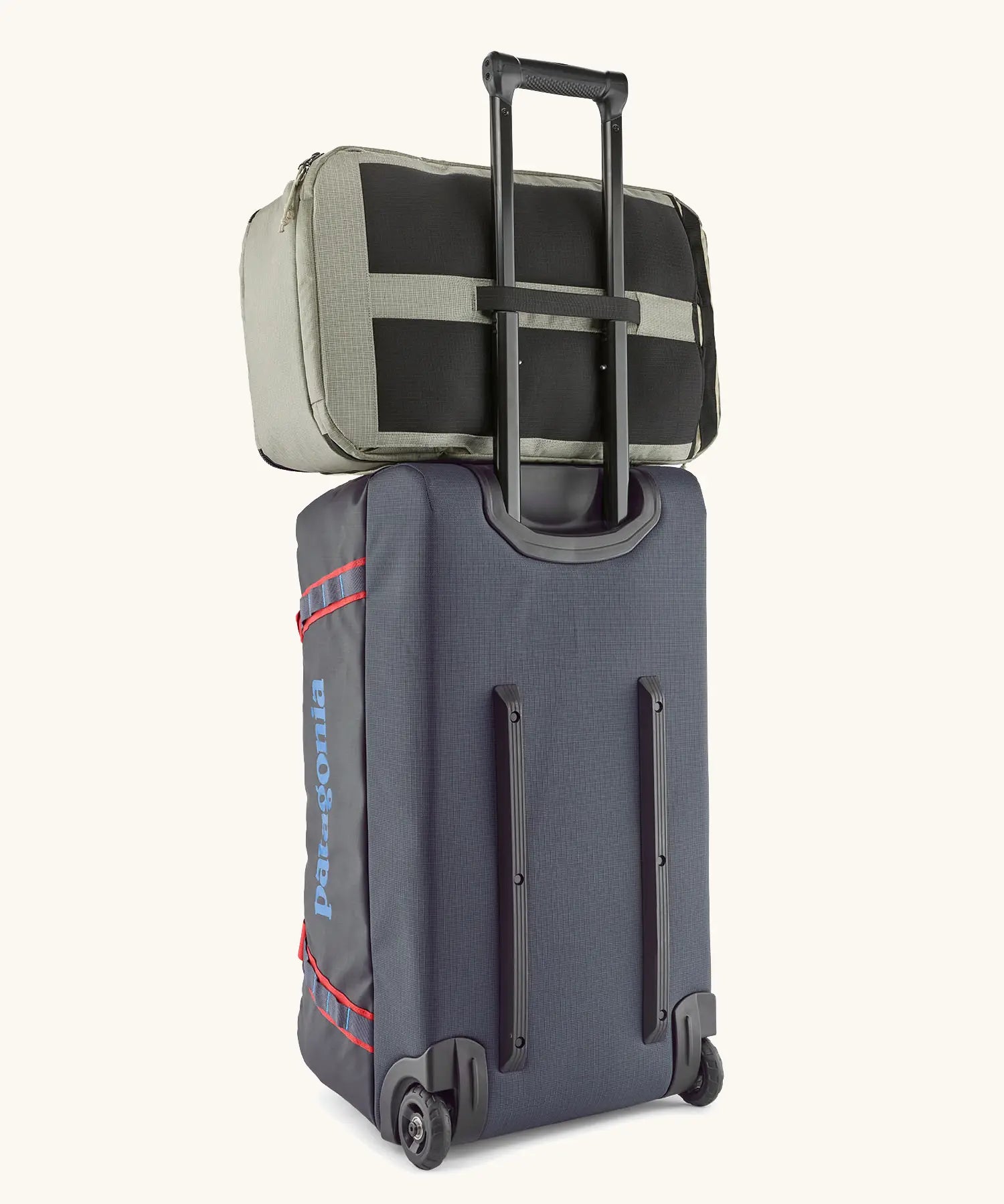 Back of the Patagonia black hole 70 litre wheeled duffel bag in dark blue showing a backpack threaded through the retractable handle 