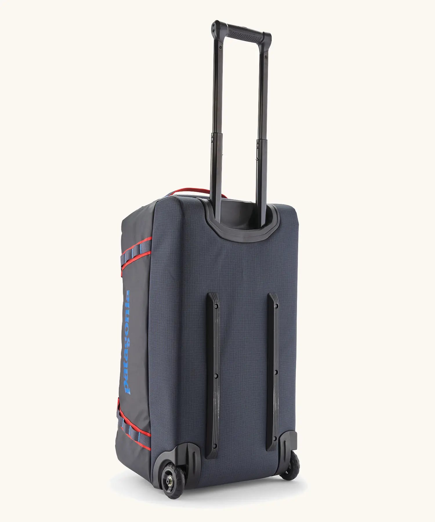 Back of the Patagonia black hole 70 litre wheeled duffel bag in dark blue showing the retractable handle and protective rails