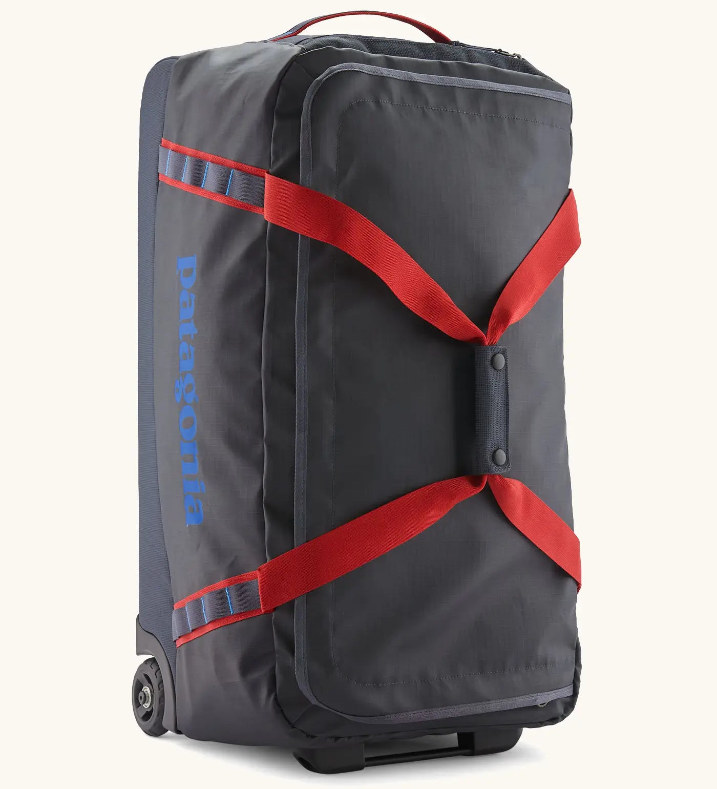 Patagonia black hole 70 litre wheeled duffel bag in dark blue with red straps. Features extra loops for attaching small items and retractable handle