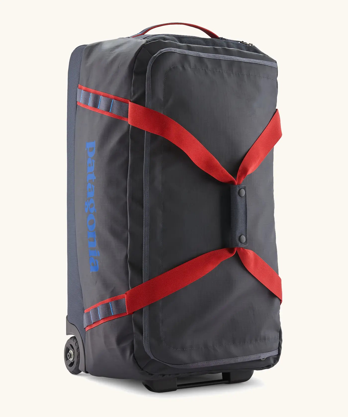 Patagonia black hole 70 litre wheeled duffel bag in dark blue with red straps. Features extra loops for attaching small items and retractable handle