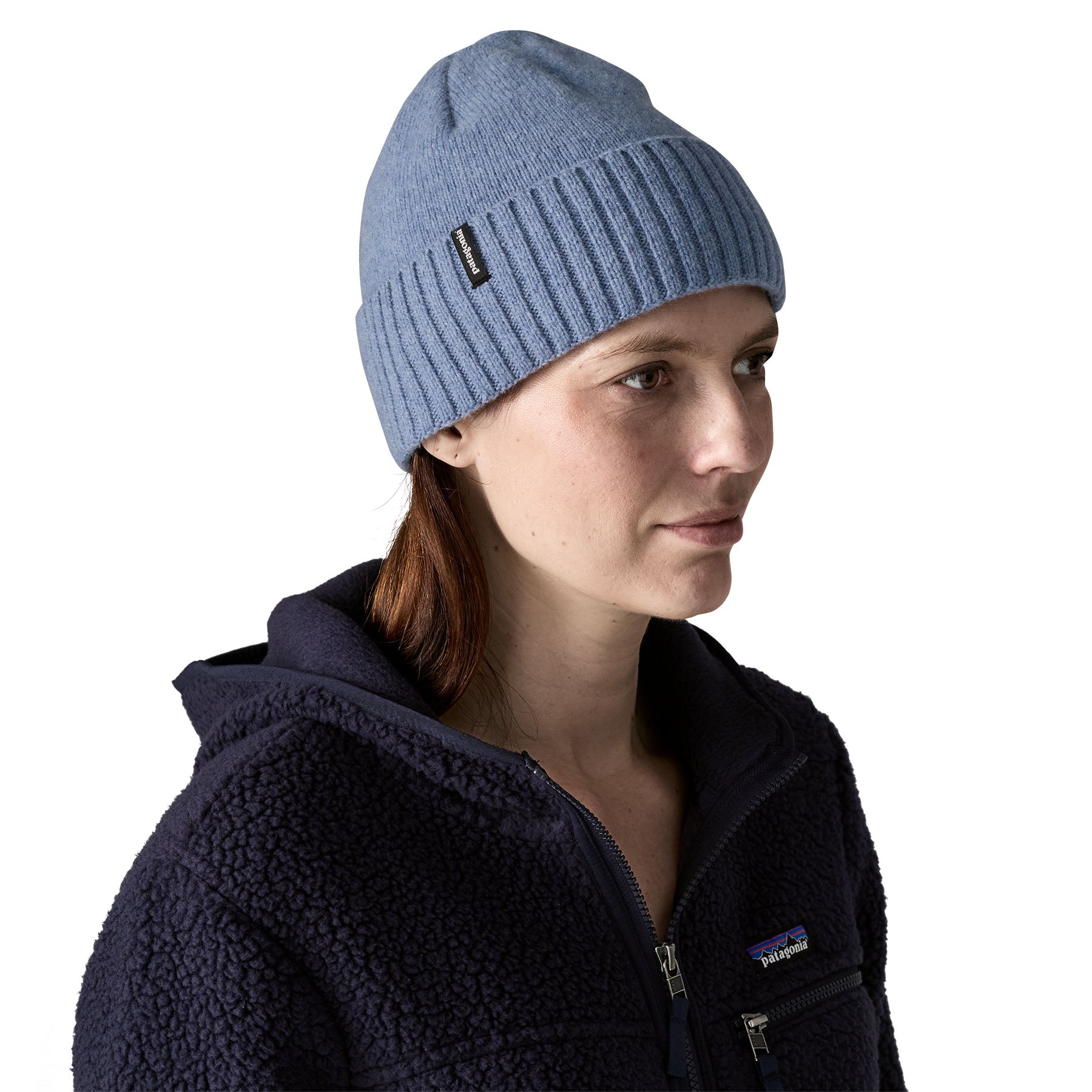 A woman wearing the Patagonia adult brodeo beanie hat on barnacle blue available at Babipur. A soft knit style beanie with turn up brim and logo patch on the side