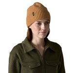 A woman wearing the Patagonia adult brodeo beanie hat in talon gold available at Babipur. A soft knit style beanie with turn up brim and logo patch on the side
