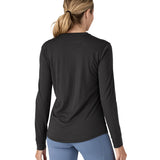 A woman modelling the Patagonia women's capilene cool merino blend long sleeve t-shirt in black available at Babipur showing the back fit