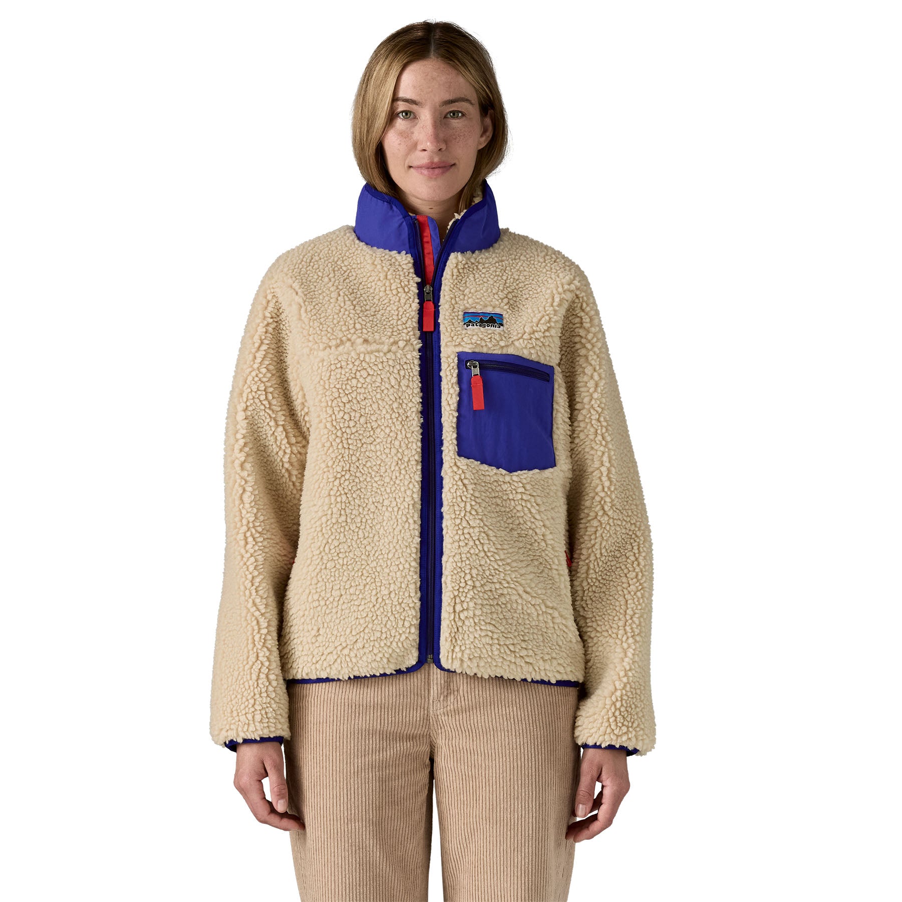 A woman wearing the Patagonia women's classic retro-x jacket in a dark natural colour way available at Babipur. A thick fleece with royal blue trim detail with a full length zip, 2 side pockets and a chest pocket with the logo patch stitched above.
