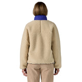 The back of a woman wearing the Patagonia women's classic retro-x jacket in a dark natural colour way available at Babipur showing the blue turn up collar detail