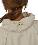 A closer look at the hood on the Patagonia Women's Torrentshell 3L Rain Jacket. The image shows a person from the back wearing the jacket, with an elasticated clip on the hood to keep the inside of the hood dry