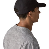 Man wearing Patagonia's organic cotton fitz roy icon trad cap in black. Shows the adjustable strap on the back