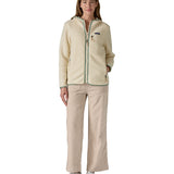 A woman wearing the Patagonia Retro Pile Hoody in natural/ellwood green available at Babipur. 