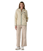 A woman wearing the Patagonia Retro Pile Hoody in natural/ellwood green available at Babipur. 