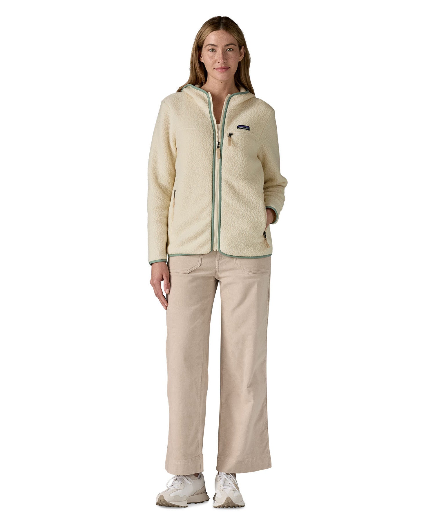 A woman wearing the Patagonia Retro Pile Hoody in natural/ellwood green available at Babipur. 