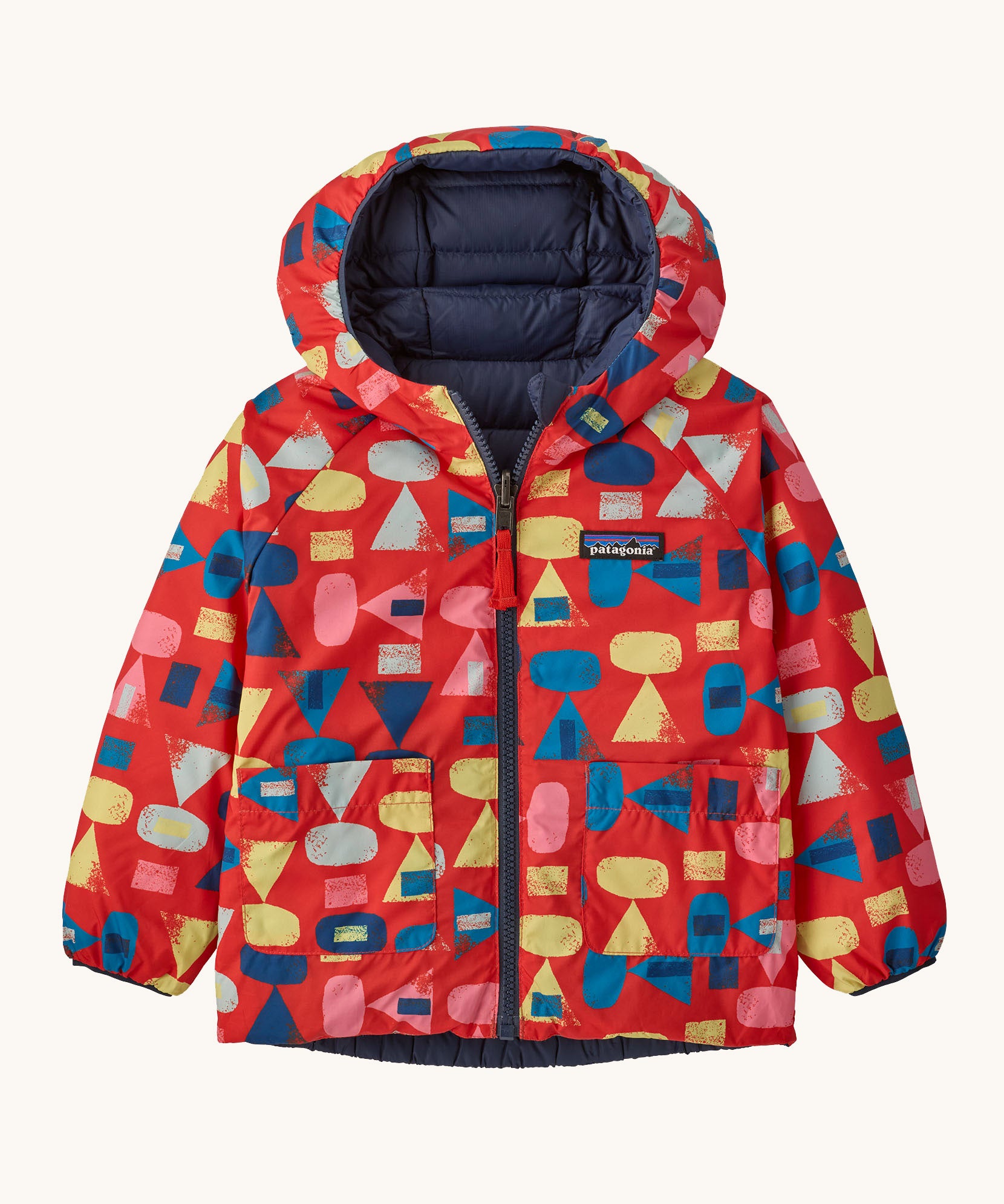 Patagonia little kids down hooded jacket in forest being sizzle red. A light warm reversible jacket in red with retro mulitcoloured shapes. Features a a full length zip and 2 side pouch pockets