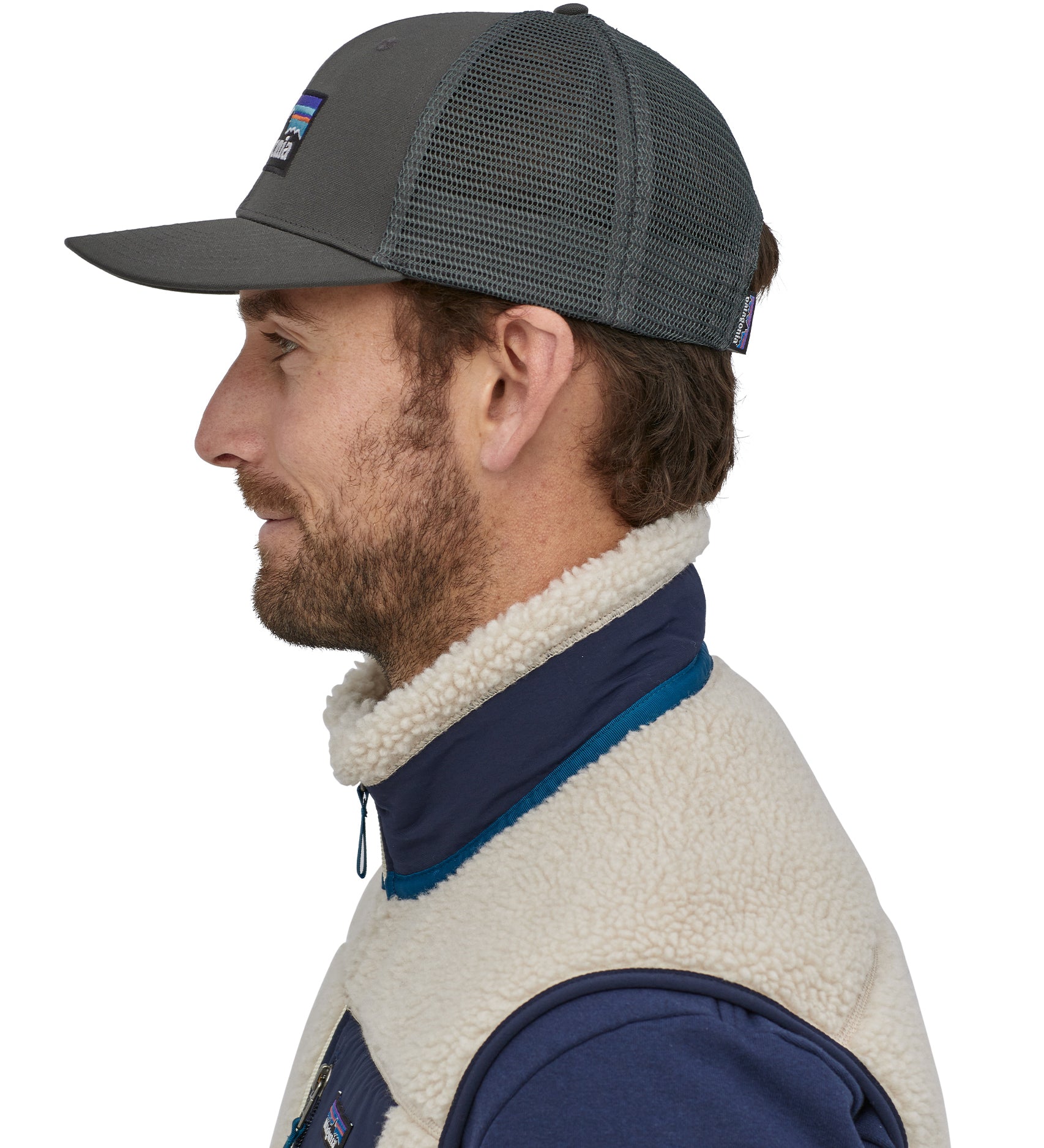 A person wearing the Patagonia P-6 Logo Trucker Hat - Forge Grey, showing it from the side to show the mesh at the back