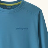 Close up of Patagonia kids long sleeve capilene tshirt in bright blue showing brand name on chest and light green trim on inner collar
