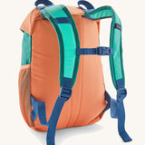 Patagonia kids refugito 12L day pack in green and pale orange block colour. Shows blue shoulder straps and orange back panel