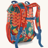 Patagonia kids refugito 12L day pack in red with a repeating tropical flower design. Shows shoulder straps with blue buckle 