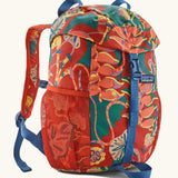 Patagonia kids refugito 12L day pack in red with a repeating tropical flower design. Shows front buckle lid fastener and mesh pockets
