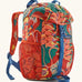 Patagonia kids refugito 12L day pack in red with a repeating tropical flower design. Shows front buckle lid fastener and mesh pockets