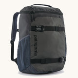 Patagonia refugito 18 litres daypack in sunken blue. A black backpack made from 100% recycled materials and features 2 side mesh pockets, buckle fasteners on the front to keep it secure and a zip on the top for easy access.