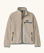 Patagonia Kids Retro Pile Jacket in Dark Natural. Cream fleece body with light sage green binding and zip pockets with pale yellow details.