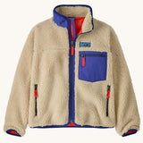 Patagonia kids retro x jacket in dark natural available at Babipur.. A 100% recycled polyester thick pile fleece in cream with blue trim. Features a turn up collar, full length zip , 2 side pockets and a chest pocket.