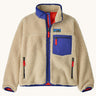 Patagonia kids retro x jacket in dark natural available at Babipur.. A 100% recycled polyester thick pile fleece in cream with blue trim. Features a turn up collar, full length zip , 2 side pockets and a chest pocket.