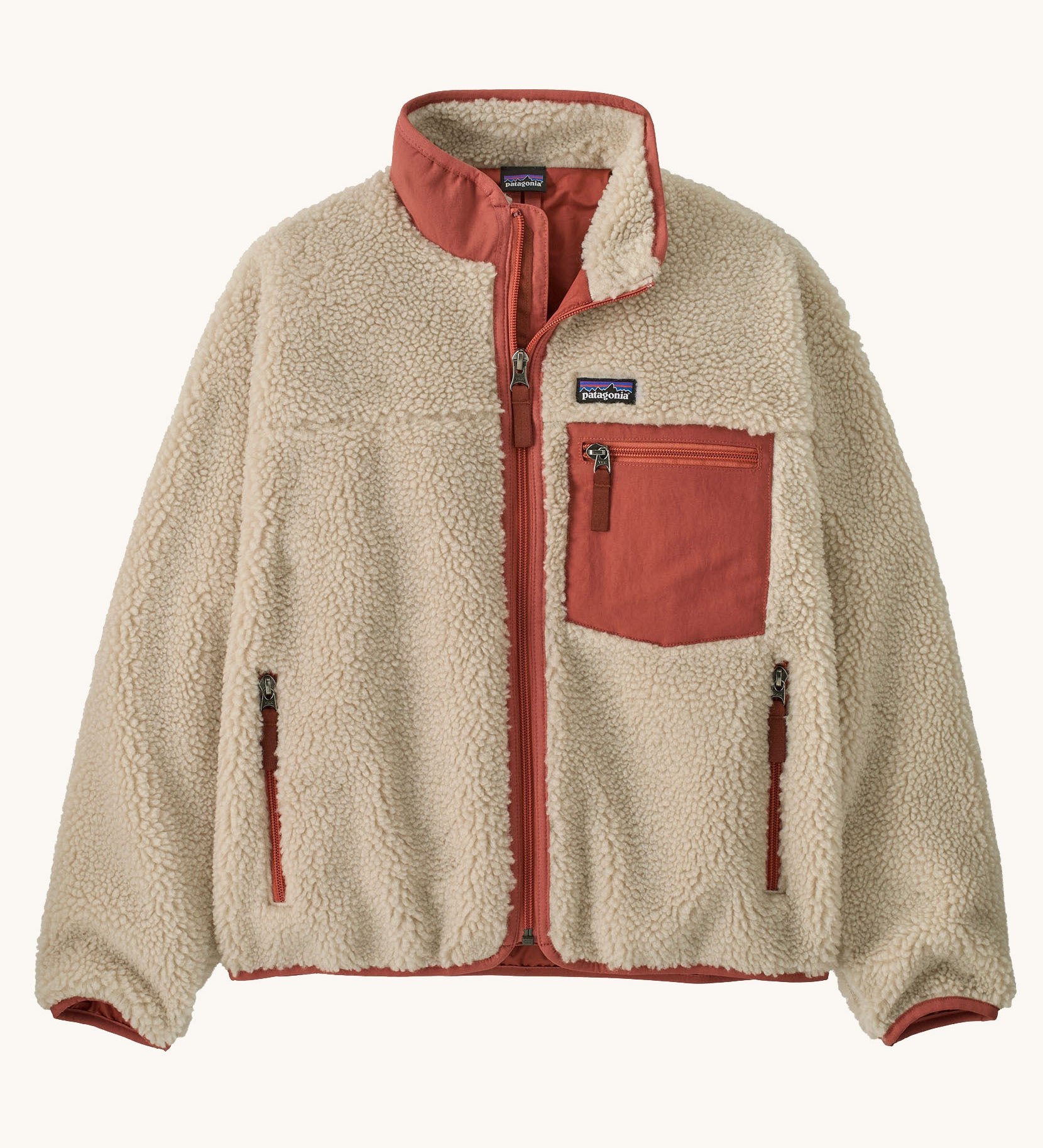 Patagonia kids retro x jacket in dark natural/potters red available at Babipur.. A 100% recycled polyester thick pile fleece in cream with pale red trim. Features a turn up collar, full length zip, 2 side pockets and a chest pocket.