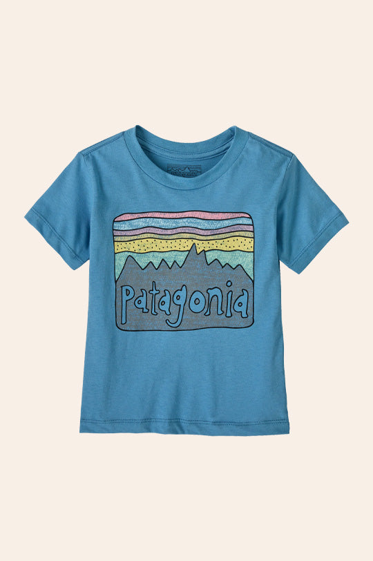 Patagonia Little Kids Fitz Roy Skies T-Shirt in Shore Blue with large Patagonia logo hand drawn, made from organic cotton, to represent new Patagonia kids clothes and gear at Babipur, official UK stockist.