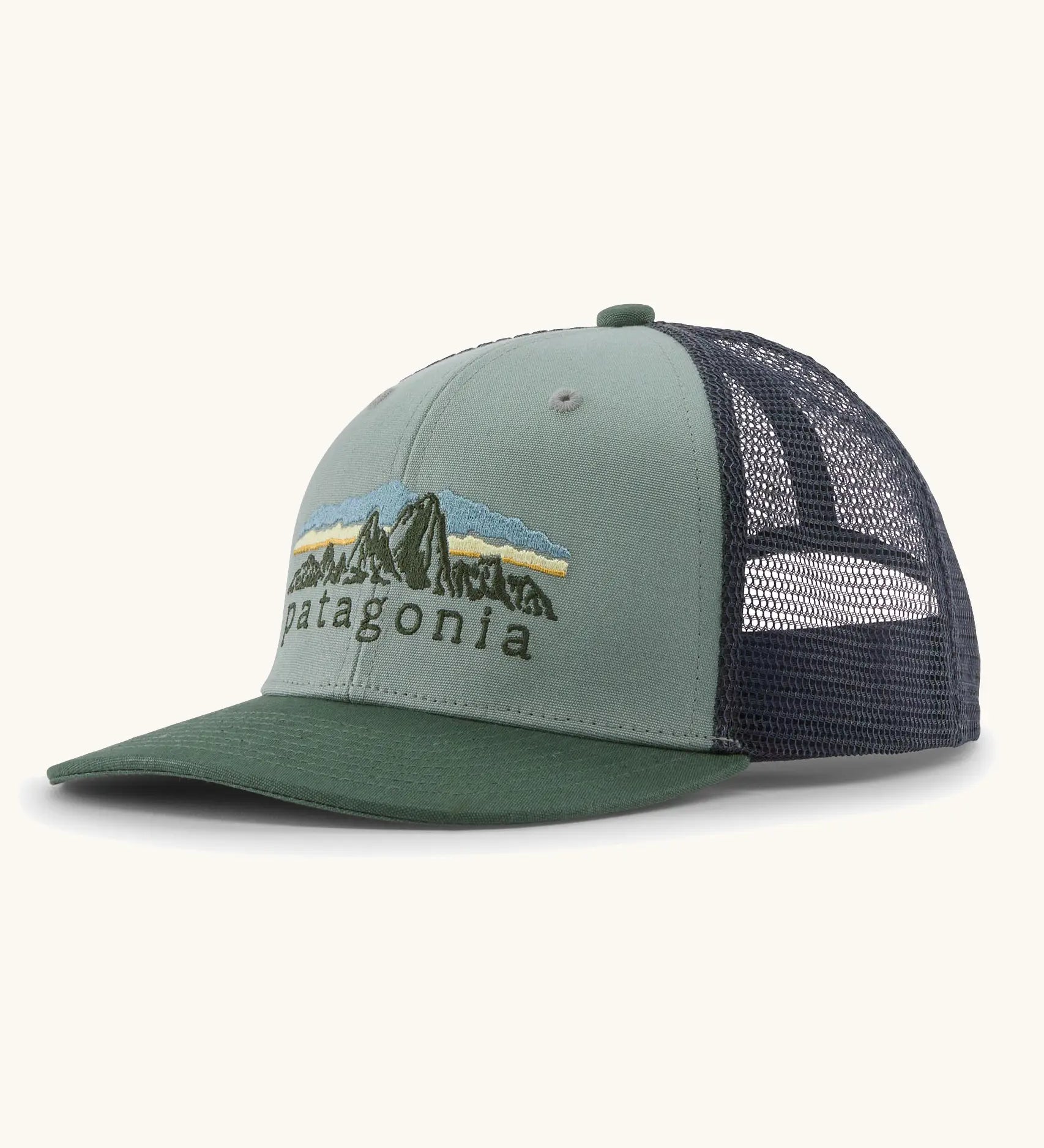Patagonia Kids Trucker hat in Cover Green. Organic sage green front crown with retro style Patagonia Fitz Roy Foothills logo, Forest green brim, and grey recycled polyester mesh back. 