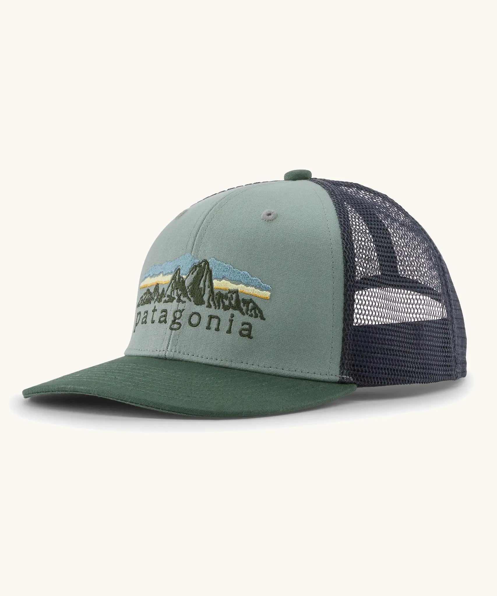 Patagonia Kids Trucker hat in Cover Green. Organic sage green front crown with retro style Patagonia Fitz Roy Foothills logo, Forest green brim, and grey recycled polyester mesh back. 