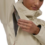 A zipped area under the arms of the Patagonia Women's Torrentshell 3L Rain Jacket, to show the jacket is breathable. A person is wearing the jacket and is showing the fabric area inside the coat under the arms