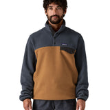 A man wearing the Patagonia mens synchilla deer brown jacket available at Babipur. A lightweight fleece in dark blue and brown colour. Features a chest pocket, logo patch stitched above and a 1/4 length popper fastener.