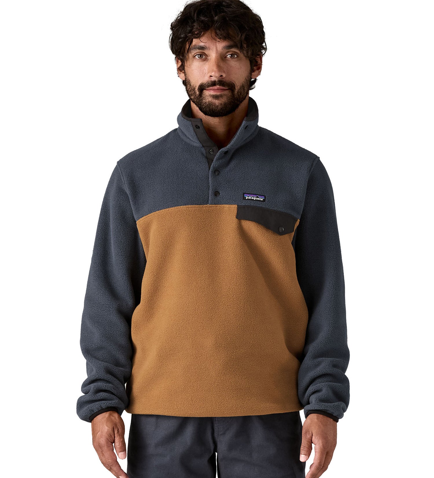 A man wearing the Patagonia mens synchilla deer brown jacket available at Babipur. A lightweight fleece in dark blue and brown colour. Features a chest pocket, logo patch stitched above and a 1/4 length popper fastener.