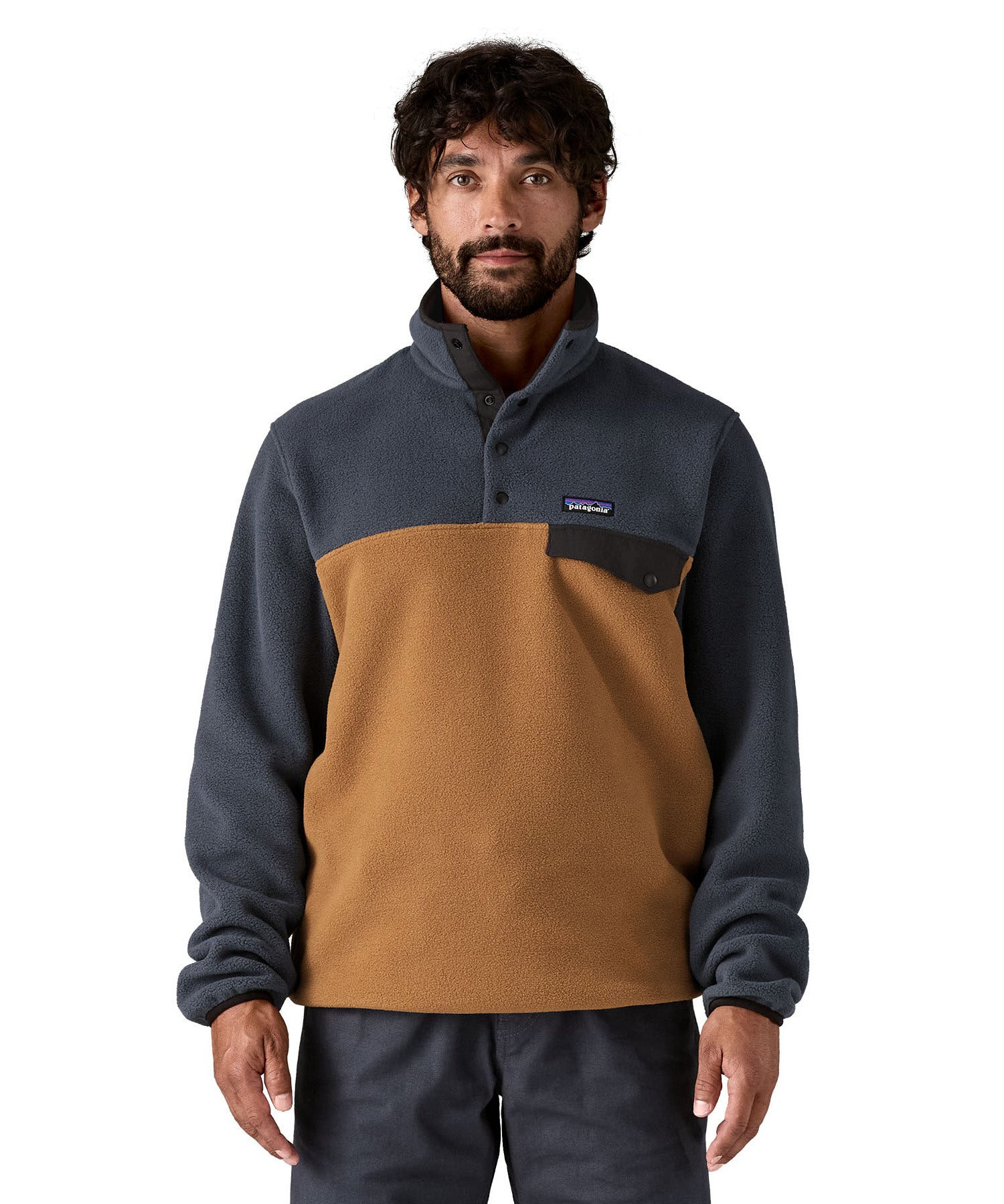 A man wearing the Patagonia mens synchilla deer brown jacket available at Babipur. A lightweight fleece in dark blue and brown colour. Features a chest pocket, logo patch stitched above and a 1/4 length popper fastener.