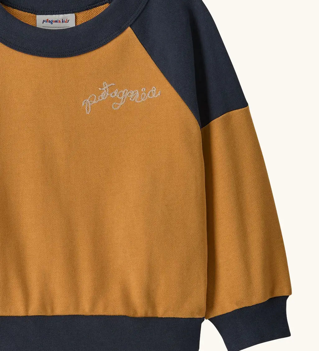Patagonia 100% organic cotton little kids crew sweatshirt in mustard yellow showing close up of the brand embroidery on the chest
