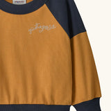 Patagonia 100% organic cotton little kids crew sweatshirt in mustard yellow showing close up of the brand embroidery on the chest