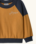Patagonia 100% organic cotton little kids crew sweatshirt in mustard yellow showing close up of the brand embroidery on the chest