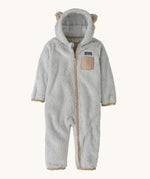Patagonia little kids furry fiends bunting suit in crisp grey available at Babipur. A 100% recycled polyester thick fleece all in one in light grey with light brown trim and matching bear like ears on the hood. Features a full length zip, elasticated cuffs and a small chest pocket