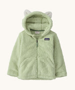 Patagonia little kids furry friends hoody in lichen green available at Babipur. A 100% recycled polyester thick fleece hooded jacket in pale green with white bear like ears on the hood. Features a full length zip and 2 side pockets.