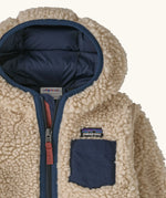 Patagonia little kids retro x pile windproof hooded fleece jacket in beige with a navy inner showing close up the chest pocket and front zip