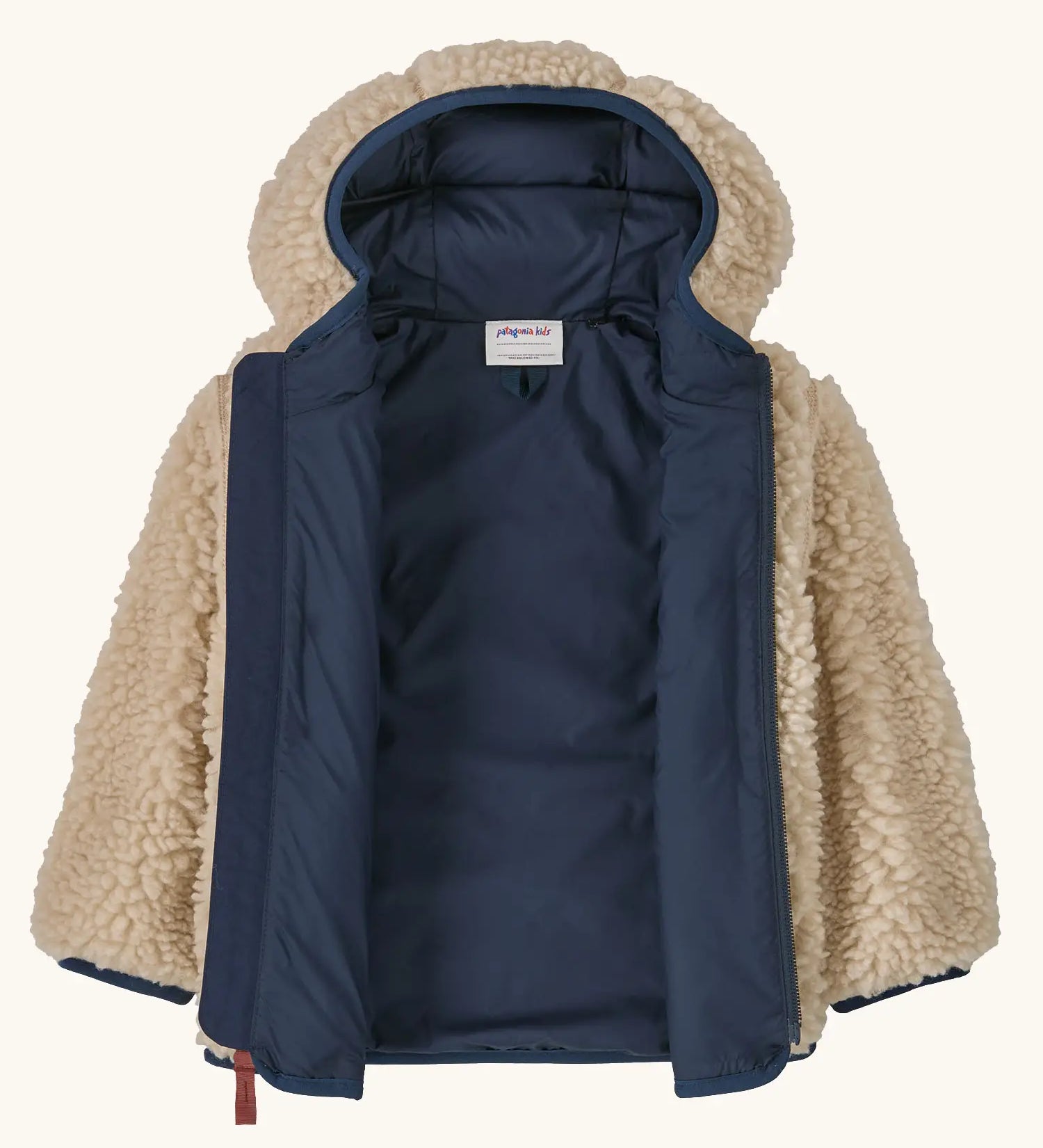 An open Patagonia little kids retro x pile windproof hooded fleece jacket in beige showing the navy inner liner
